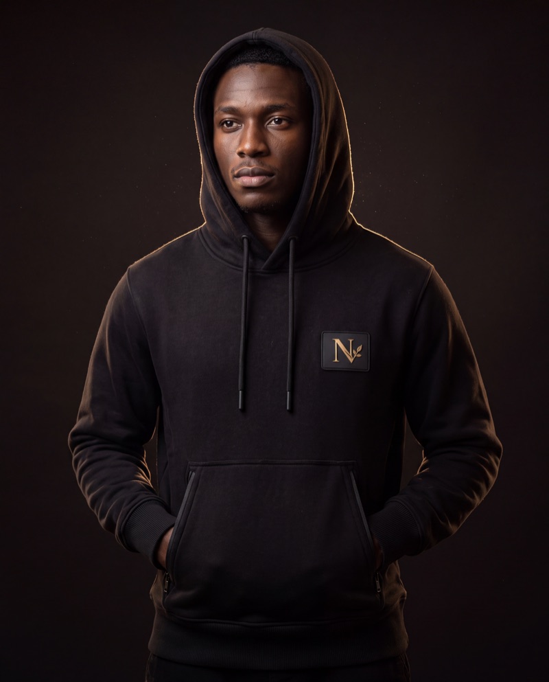 Model wearing the Rooted Hoodie with the hood up in a dark studio